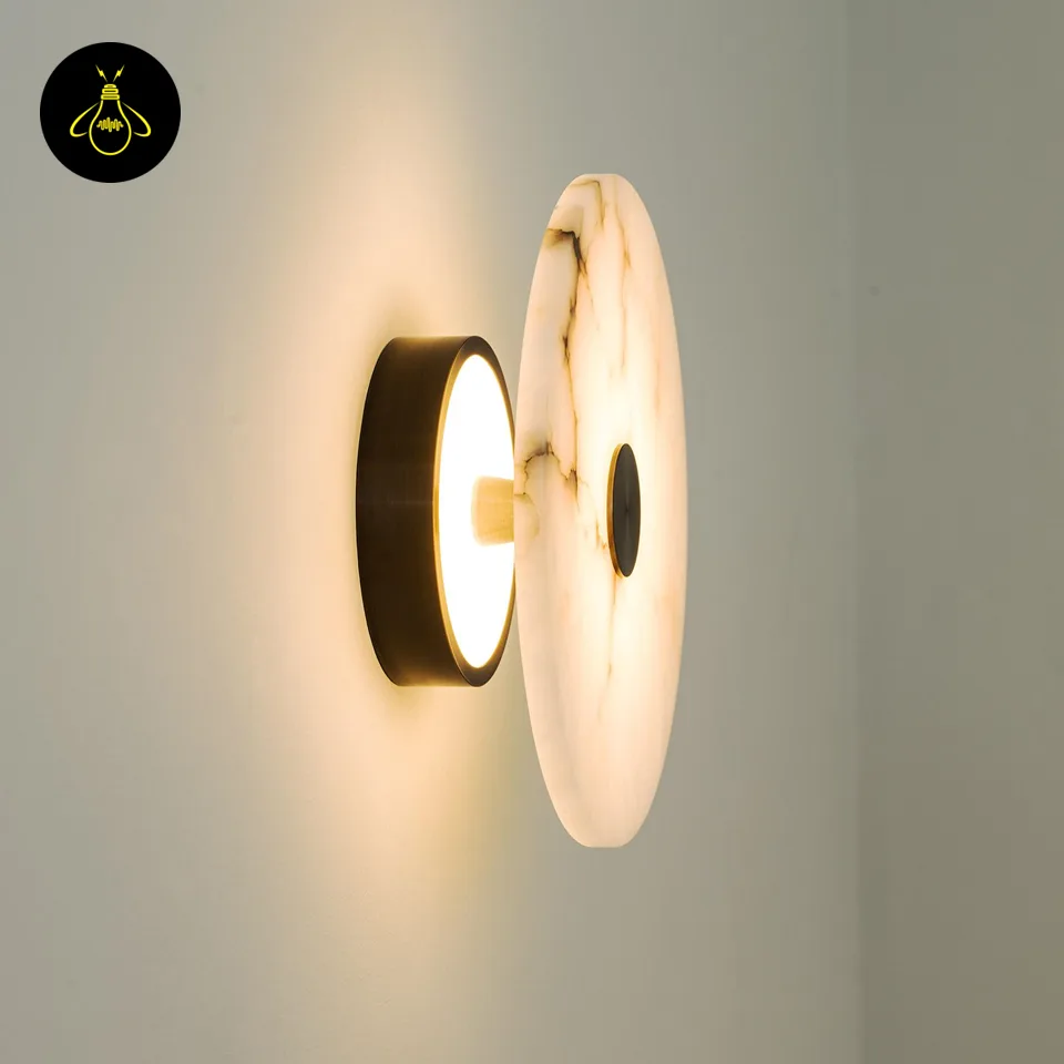 Alabaster Wall Light – Eclipse Disc Sconce, 4 Sizes | JagMag Lights 5 Alabaster wall light lit at an angle, showing the black cylindrical wall mount and warm back glow spilling onto the wall