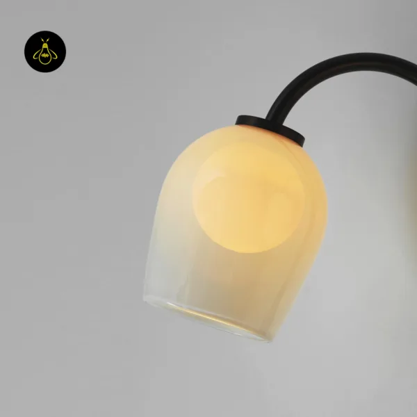 Opal borosilicate glass dome of a gooseneck wall sconce glowing warm, the E14 bulb softened inside the glass