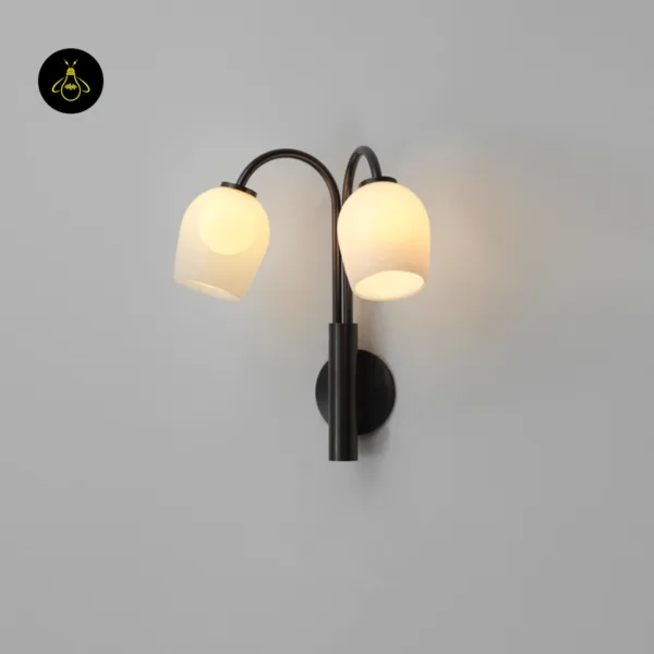 Gooseneck wall sconce lit and seen at an angle, curved dark bronze arms holding opal borosilicate glass domes out from the wall