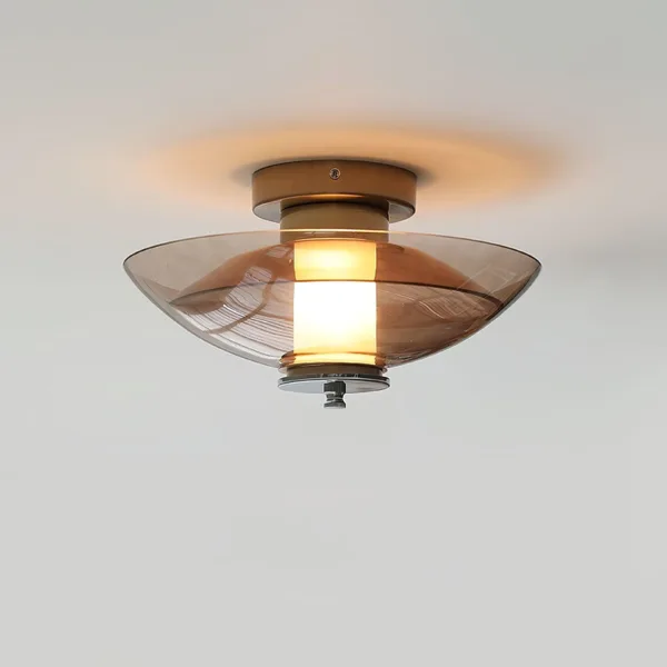 Amber glass wall light fixed to a ceiling, the amber borosilicate glass saucer glowing around an opal borosilicate glass cylinder