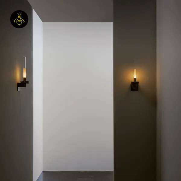 Pair of candle wall lights glowing warm on facing walls of a corridor