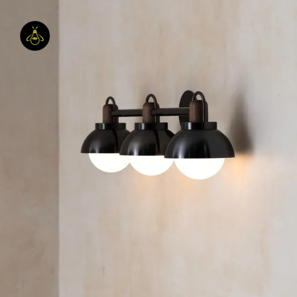 Vanity wall light seen from the side: three opal globes in a row, black stainless steel domes and walnut collars