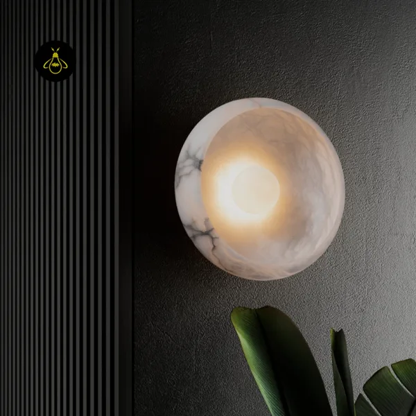 Round wall sconce in alabaster lit warm on a dark textured wall, grey veins in the stone rim around a glowing opal globe