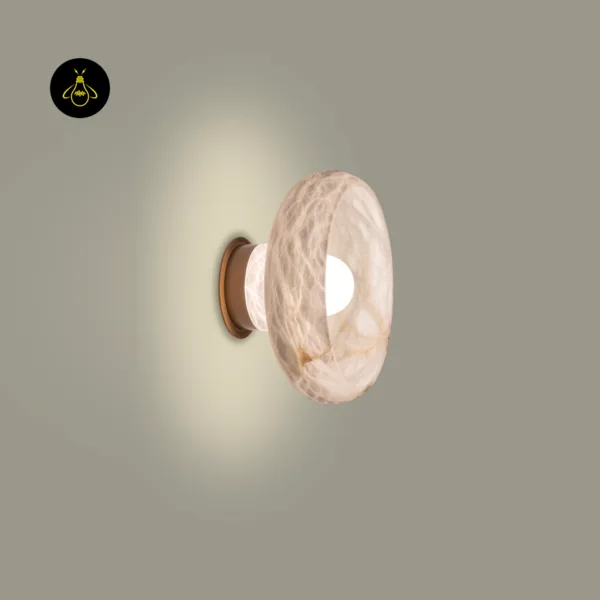 Round wall sconce in alabaster switched on, side view with a warm halo on the wall and a brass-finish round backplate