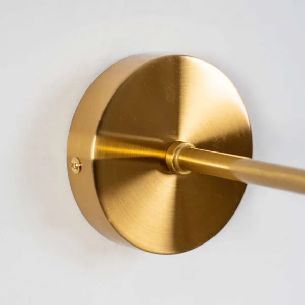 Close-up of the round backplate and arm of the dome wall light, antique brass finish on 304-grade stainless steel