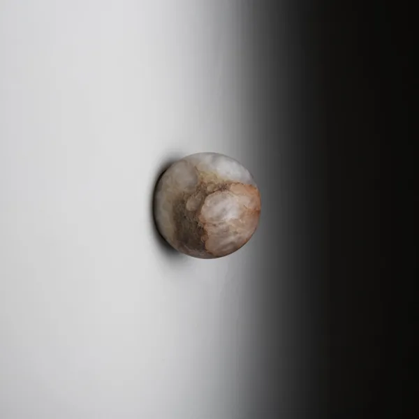 Alabaster wall light, unlit side view: veined natural stone globe on a slim backplate against a white wall