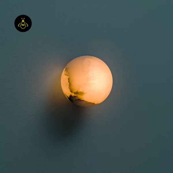 Alabaster wall light switched on, warm glow through the veined stone globe on a blue-grey wall