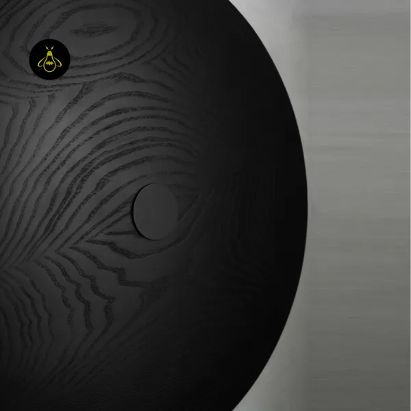 Close-up of the wooden wall light: black solid-wood grain and the matte black centre cap