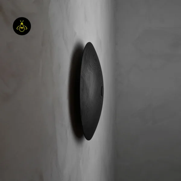 Wooden wall light in profile, showing the domed matte black wood disc standing off the wall