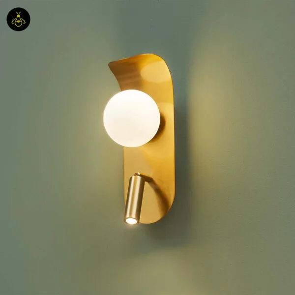 Bedroom reading light on a sage green wall, opal borosilicate glass globe glowing above a brushed gold leaf and reading spot