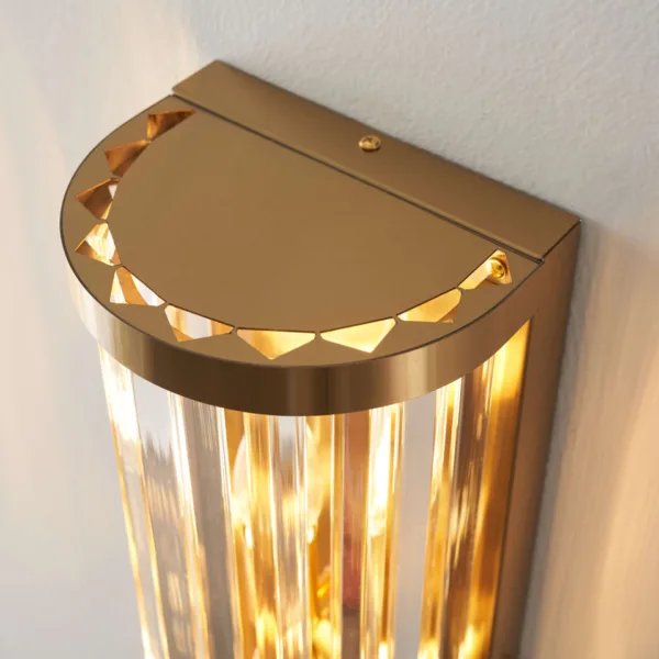 Close-up of the ribbed glass wall light top cap from above, small triangles catching the warm glow over the glass rods