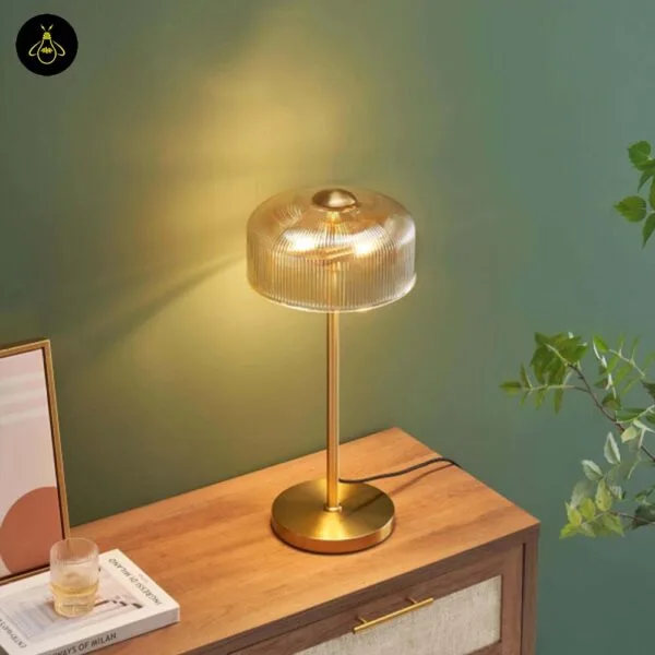 Ribbed amber glass table lamp lit with a warm golden glow