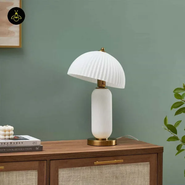 Warm-lit fluted glass mushroom table lamp on a sideboard