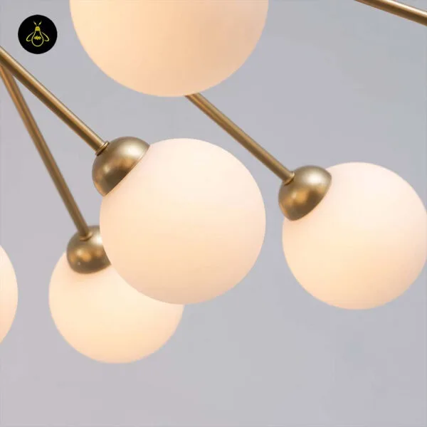 Close-up of opal borosilicate glass globes on the gold chandelier's brass arms
