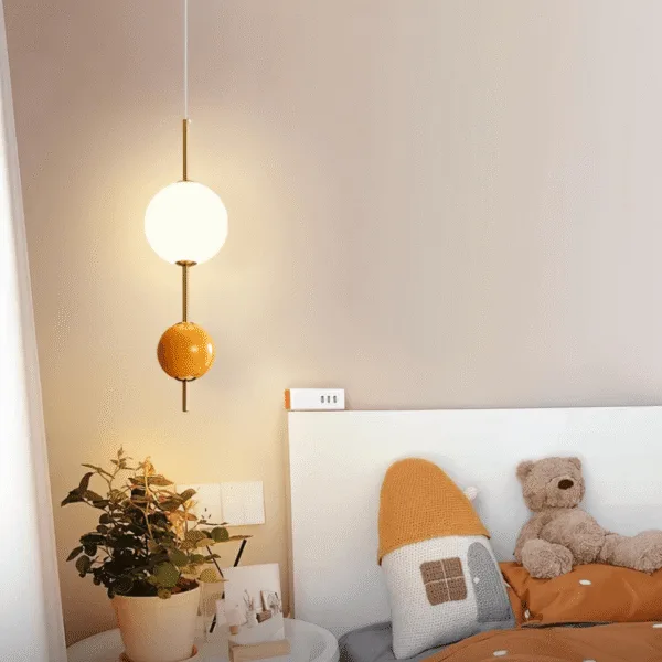 Round ball pendant light lit beside a bed in a child's bedroom, hanging over the bedside table