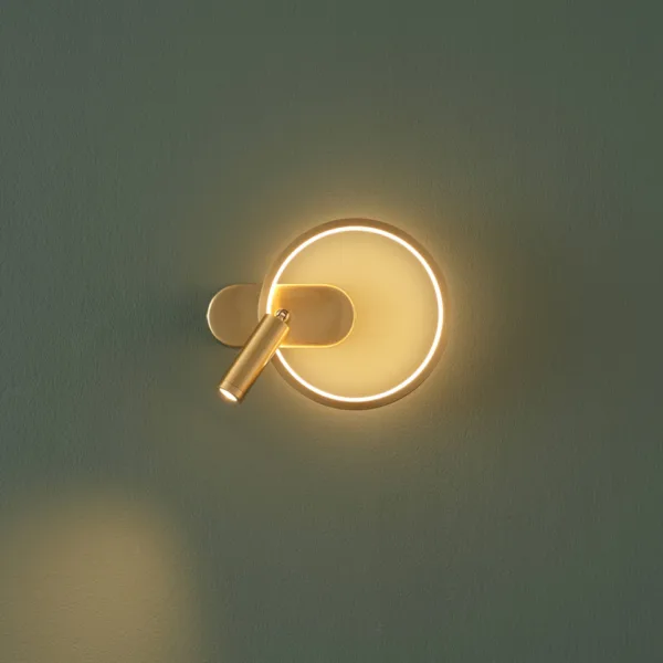 Gold circle wall light seen from the side, reading spot turned to the left