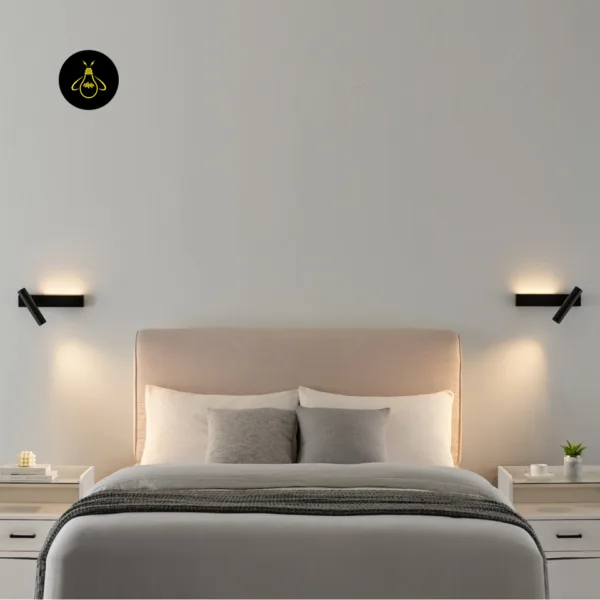 A pair of black wall reading lamps on either side of a bed headboard, both glowing