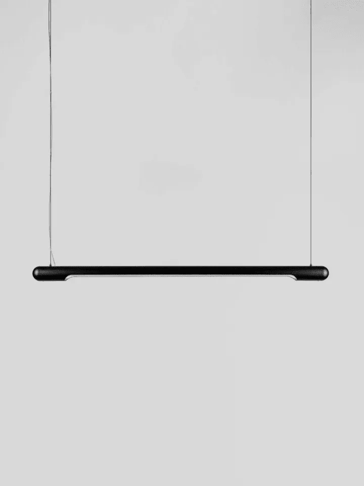 Linear chandelier in matte black, one slim LED bar hanging on two fine cables against a grey wall