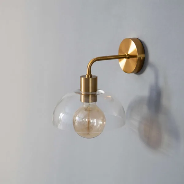 Dome wall light at an angle on a grey wall, the clear glass dome casting a soft shadow