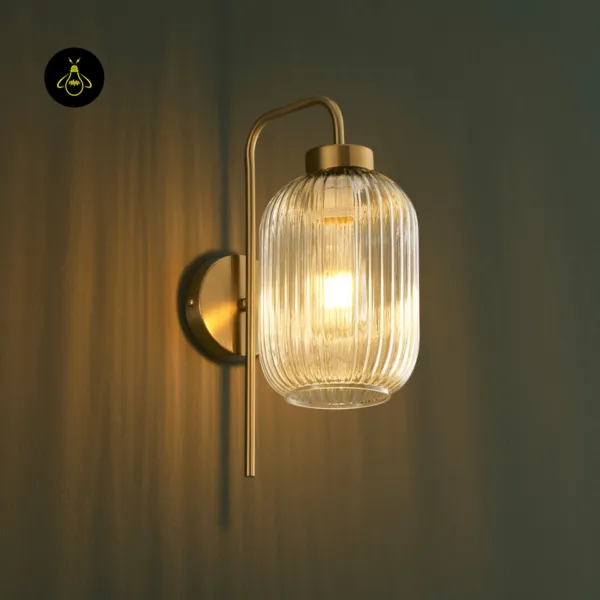 Lit fluted glass wall light close-up, ribbed glass shade glowing on a dark green wall