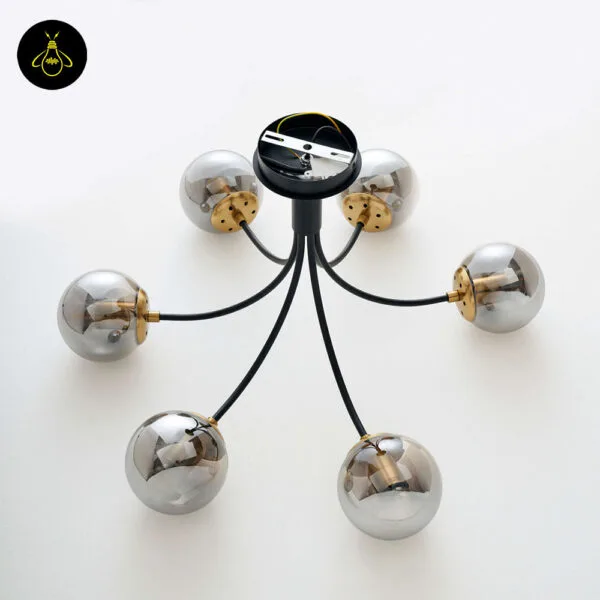 Close-up of matte-black chandelier arm and brass-finish bulb cup
