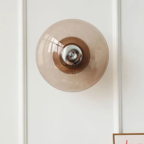 Amber glass wall light seen straight on: a round 30 cm amber borosilicate glass saucer with a chrome centre on a white wall