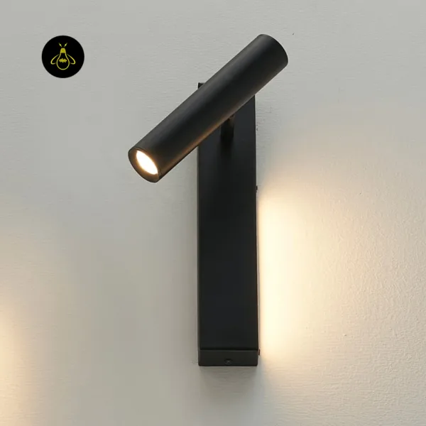 Black wall reading lamp mounted upright, reading head turned sideways, glowing on a textured wall