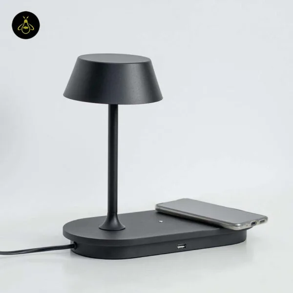 Modern matte black LED table lamp charging a phone on its wireless pad