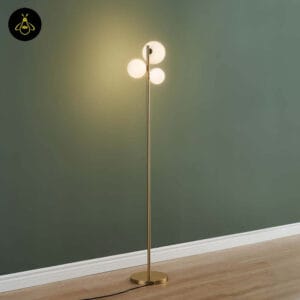 Modern gold glass globe floor lamp lit against a green accent wall