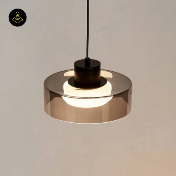 Smoked glass drum pendant light seen from below, opal core glowing inside the grey drum