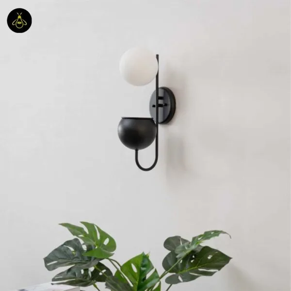 Plant pot wall light on a white wall above a monstera plant