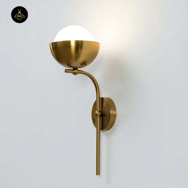 Opal white light lit on a white wall, angled view of the opal borosilicate glass globe in its brass-finish cup and curved stem