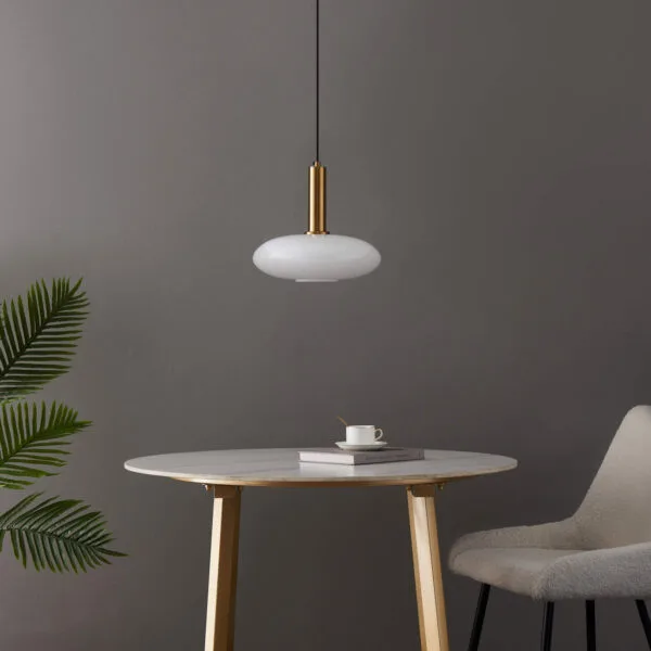 Opaline glass pendant light switched off over a round marble-top table, grey chair and palm plant against a grey wall