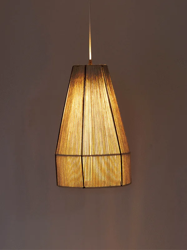 Boho pendant light with a raffia cone shade on white wire, glowing warm in front of a dusky wall