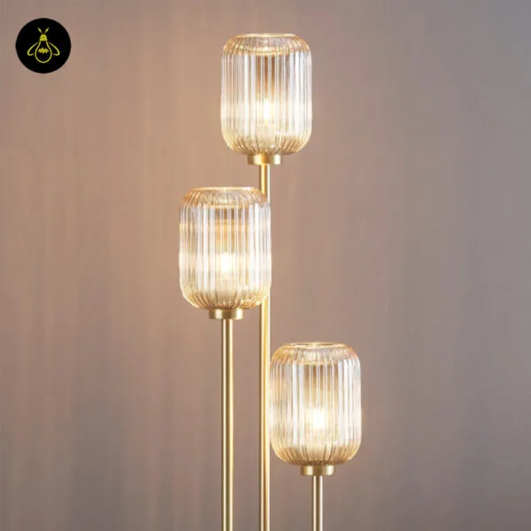 Triple amber glass floor lamp with three ribbed amber shades on a plain background