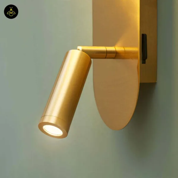 Close-up of the adjustable brushed gold LED reading spot on its pivot arm, with a rocker switch on the backplate of the bedroom reading light
