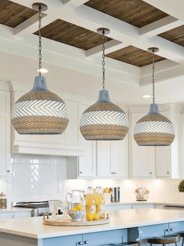 Three coastal rattan hanging lamps on black chains over a white kitchen island