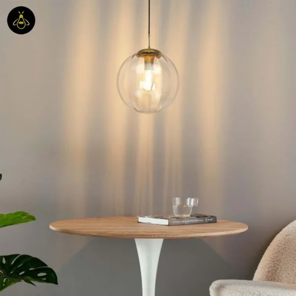 Ribbed glass ball pendant light over a round table, its ribs throwing lines of warm light up the wall