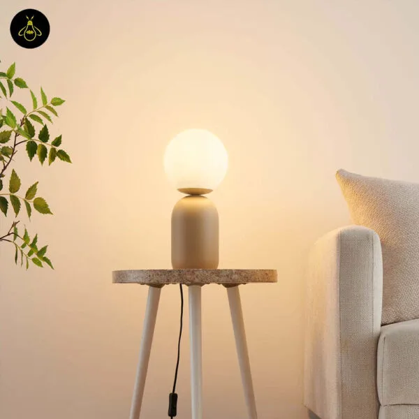 Taupe table lamp with white globe lit on a living room side table