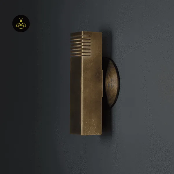 Unlit up and down wall light at an angle: antique brass finish steel column on a round wooden backplate