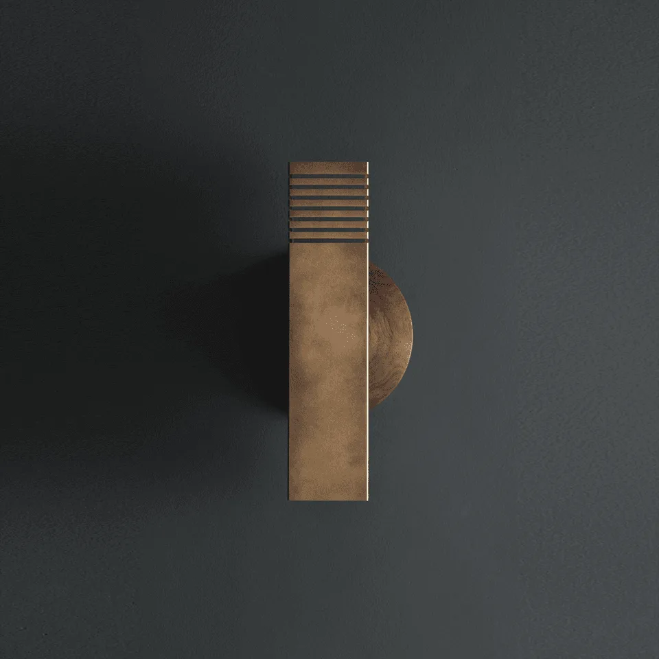 Up and down wall light in antique brass finish stainless steel on a walnut wood disc, front view on a dark wall