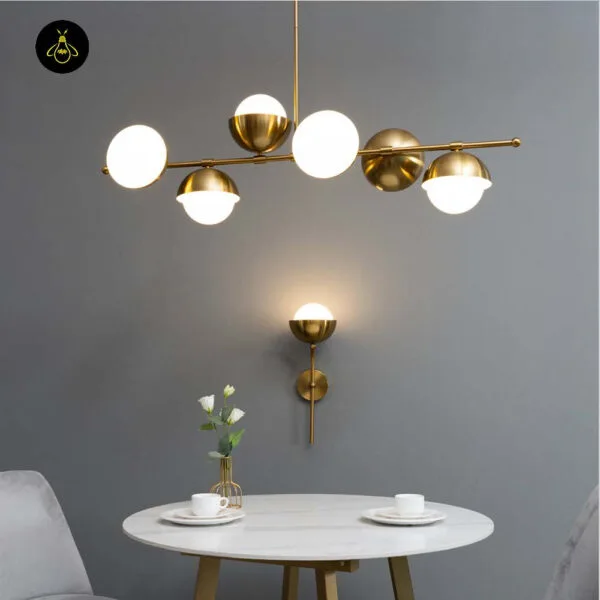 Opal white light on a grey wall under a brass globe chandelier, round marble table with white flowers and cups