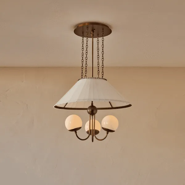 Vintage glass chandelier with three lit milk glass globes under a pleated cream shade