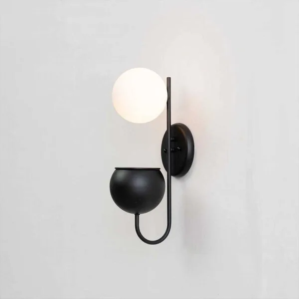 Plant pot wall light lit on a pale wall, showing globe, backplate and planter cup