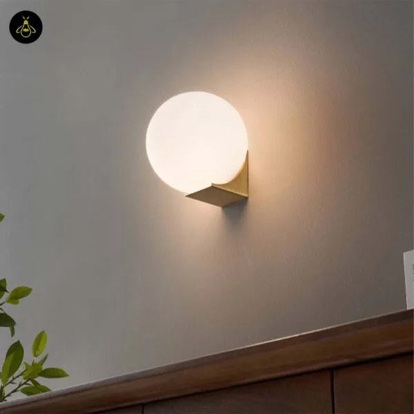 Globe wall light glowing on a grey wall above a wooden console in a hallway
