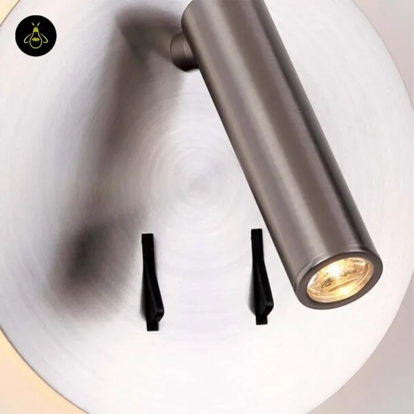 Close-up of the wall lamp for bedroom: circular brush lines on the steel disc, LED reading spot and two switches