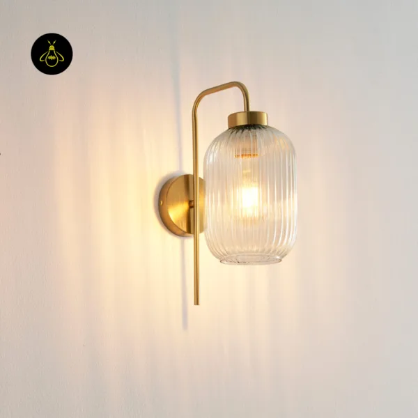 Fluted glass wall light glowing on a white wall, soft rippled light around the shade