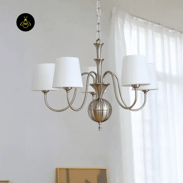 White chandelier hanging by a sheer-curtained window, silk shades on brushed nickel arms