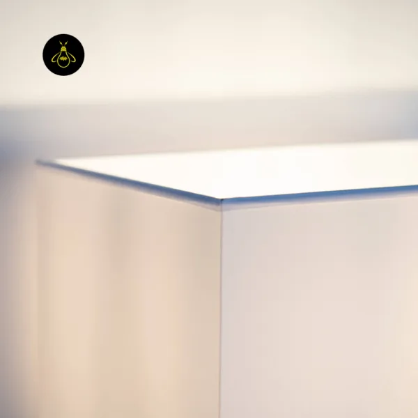 Close-up of the white fabric shade corner on the wall mounted bedside light, glowing warm