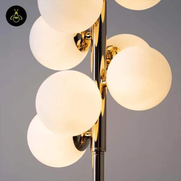 Close-up of the white globe floor lamp: lit opal glass spheres on short polished gold arms